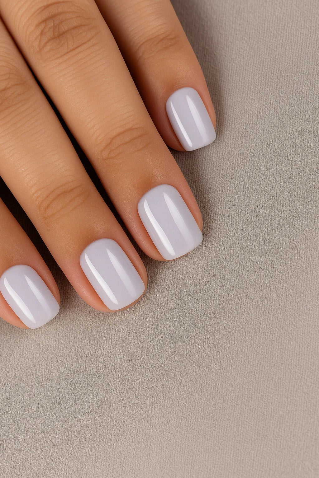 Close-up of a hand with grey lavender fake nails online on a beige background