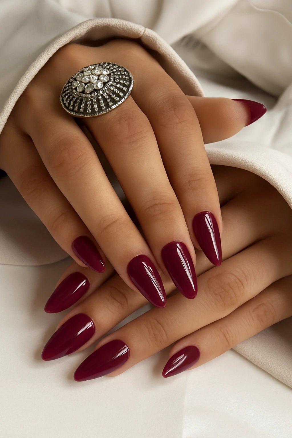 Hand with bridal press on nails wearing a decorative ring on a neutral background