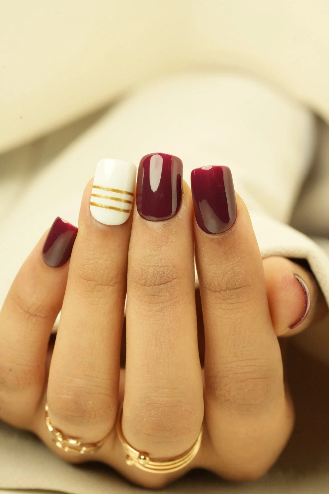 Close-up of a hand with wine red short square soft gel press on nails
background