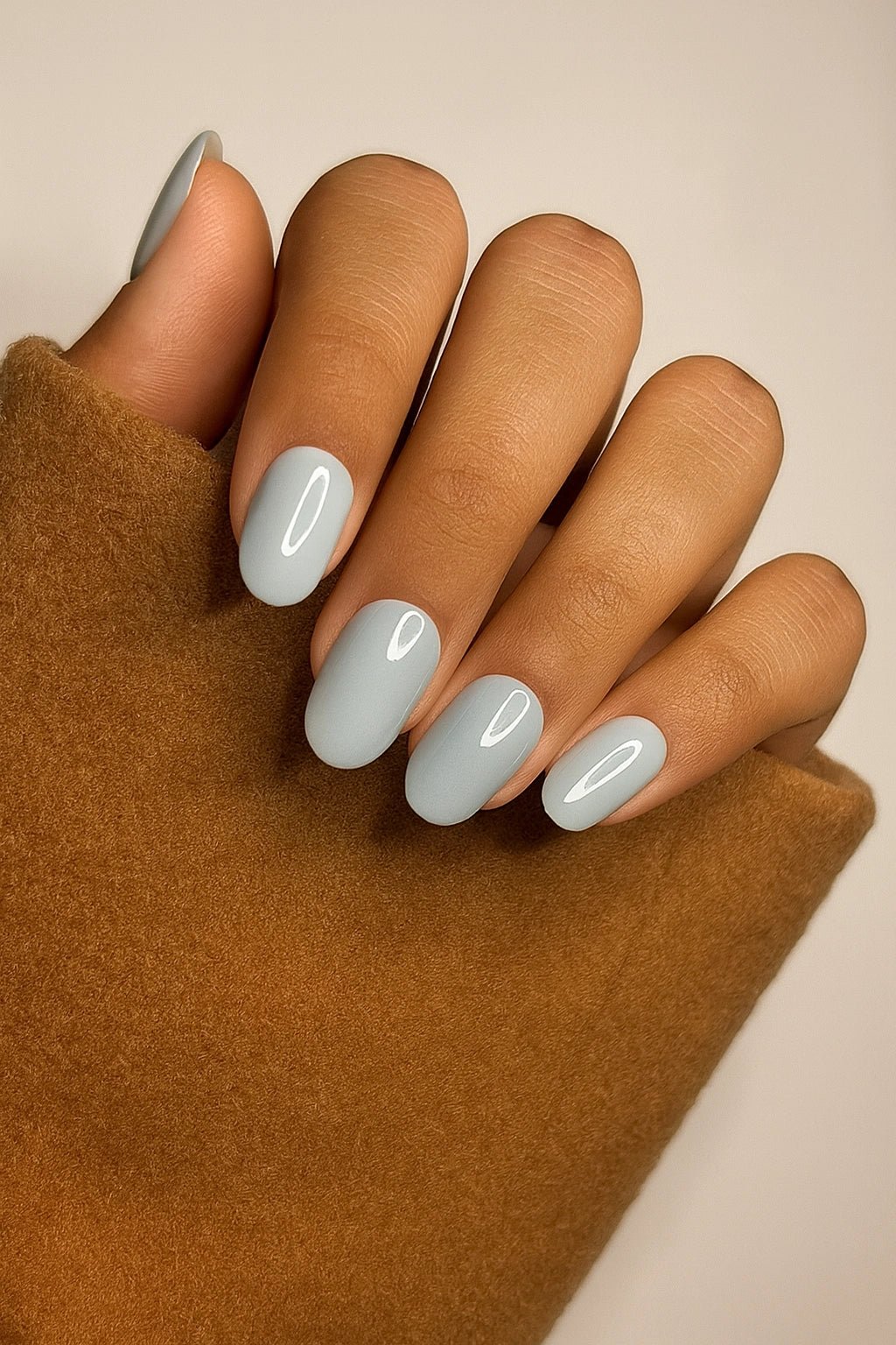 Hand with short round sea green fake nails on a neutral background