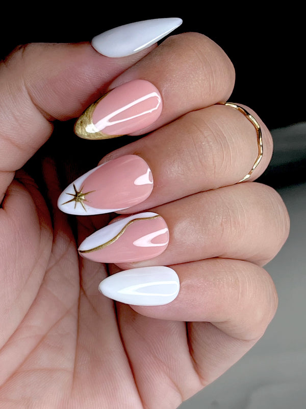 Hand with pink and white fake nails featuring gold accents