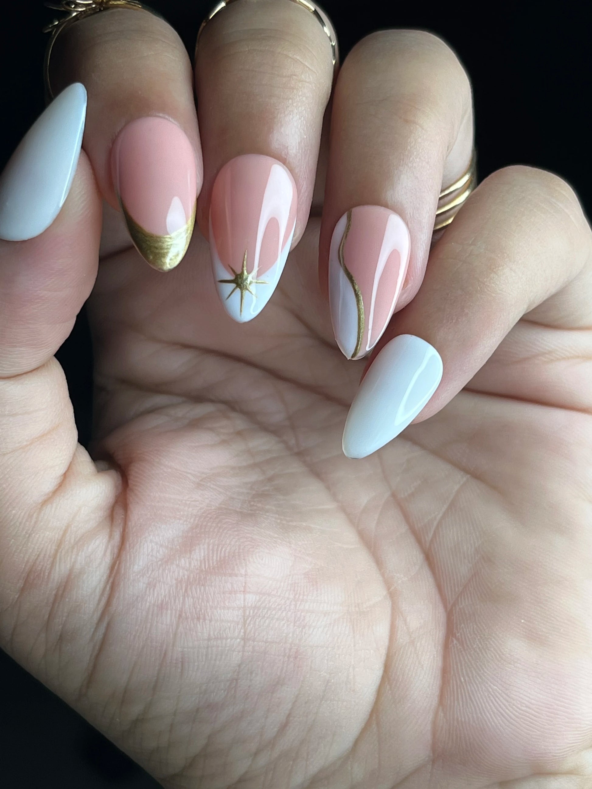 Close-up of a hand with long, stylish pink and white almond fake press on nails featuring various colors and designs.