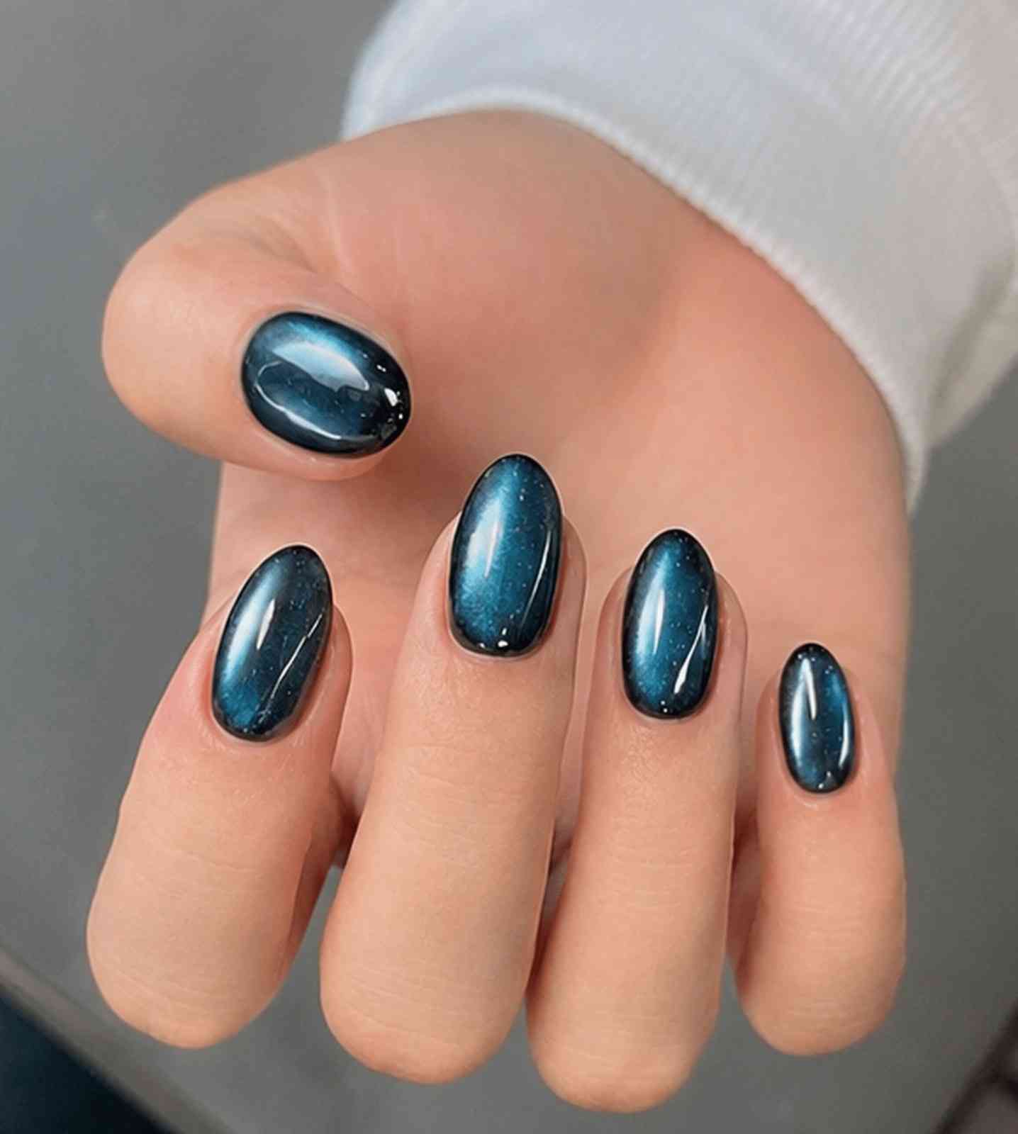 Green Galaxy reusable soft gel press-on nails with a mesmerizing green cat-eye effect on a black base by Naakhun.