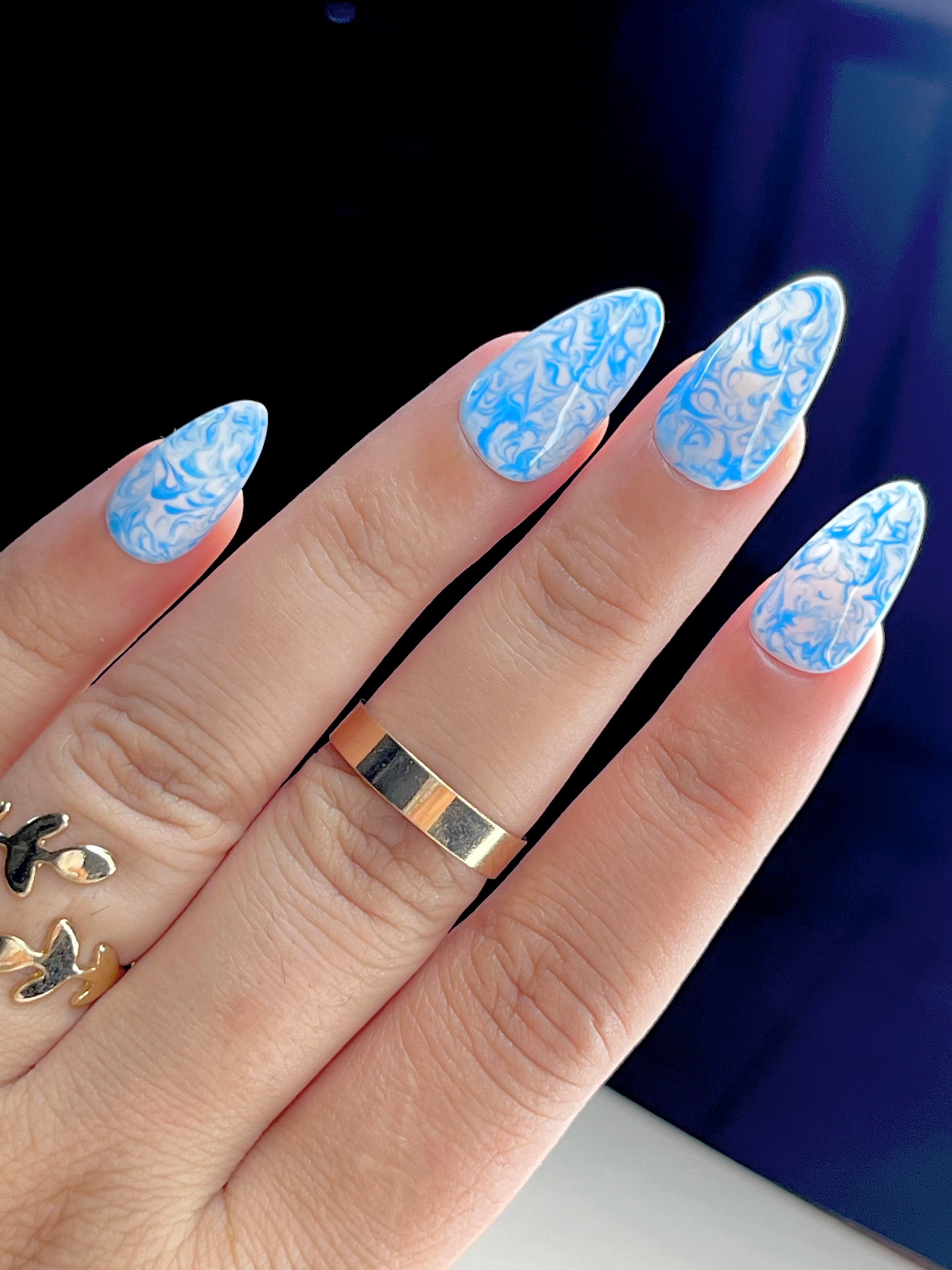 Blue and white marble press-on nails with swirl nail art design

