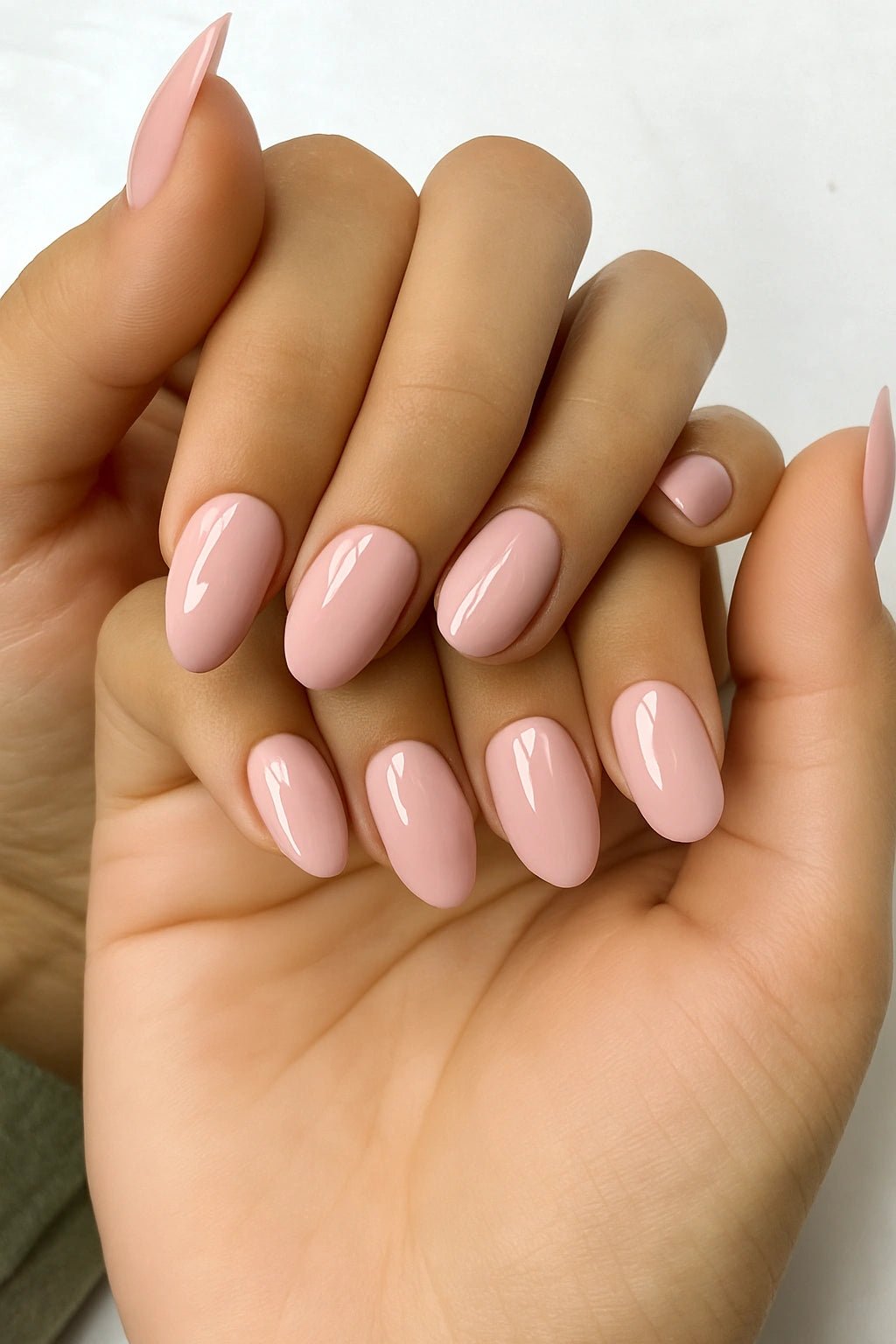 Hand with nude pink nails on a white background