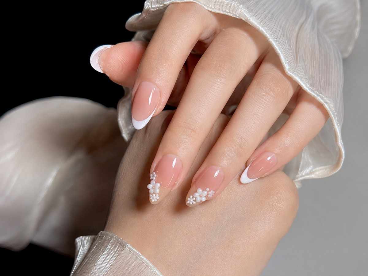 Close-up of Pearl Petals nails highlighting floral details, pearl embellishments, and a glossy finish.