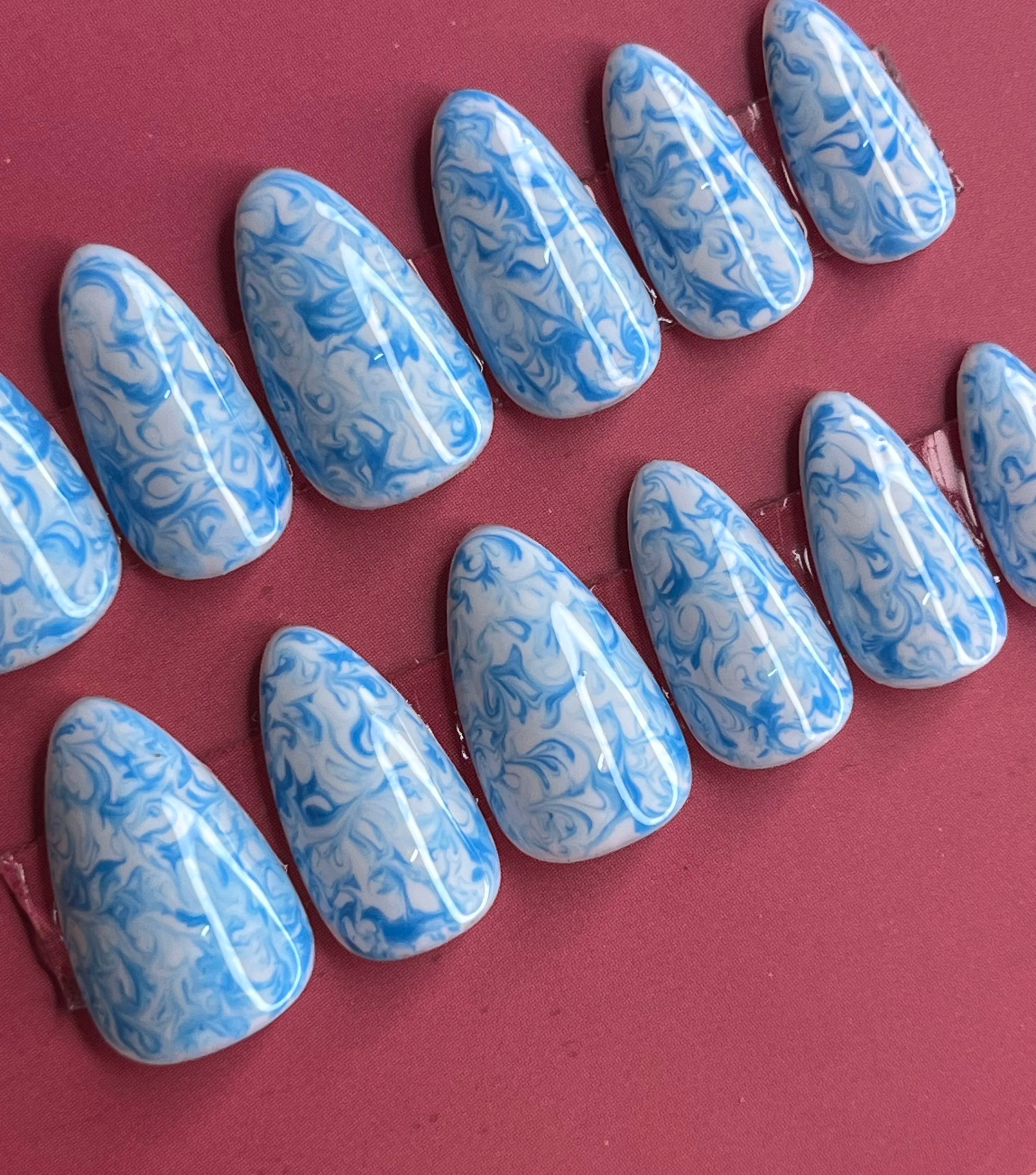 Elegant blue press-on nails with marble texture and glossy finish


