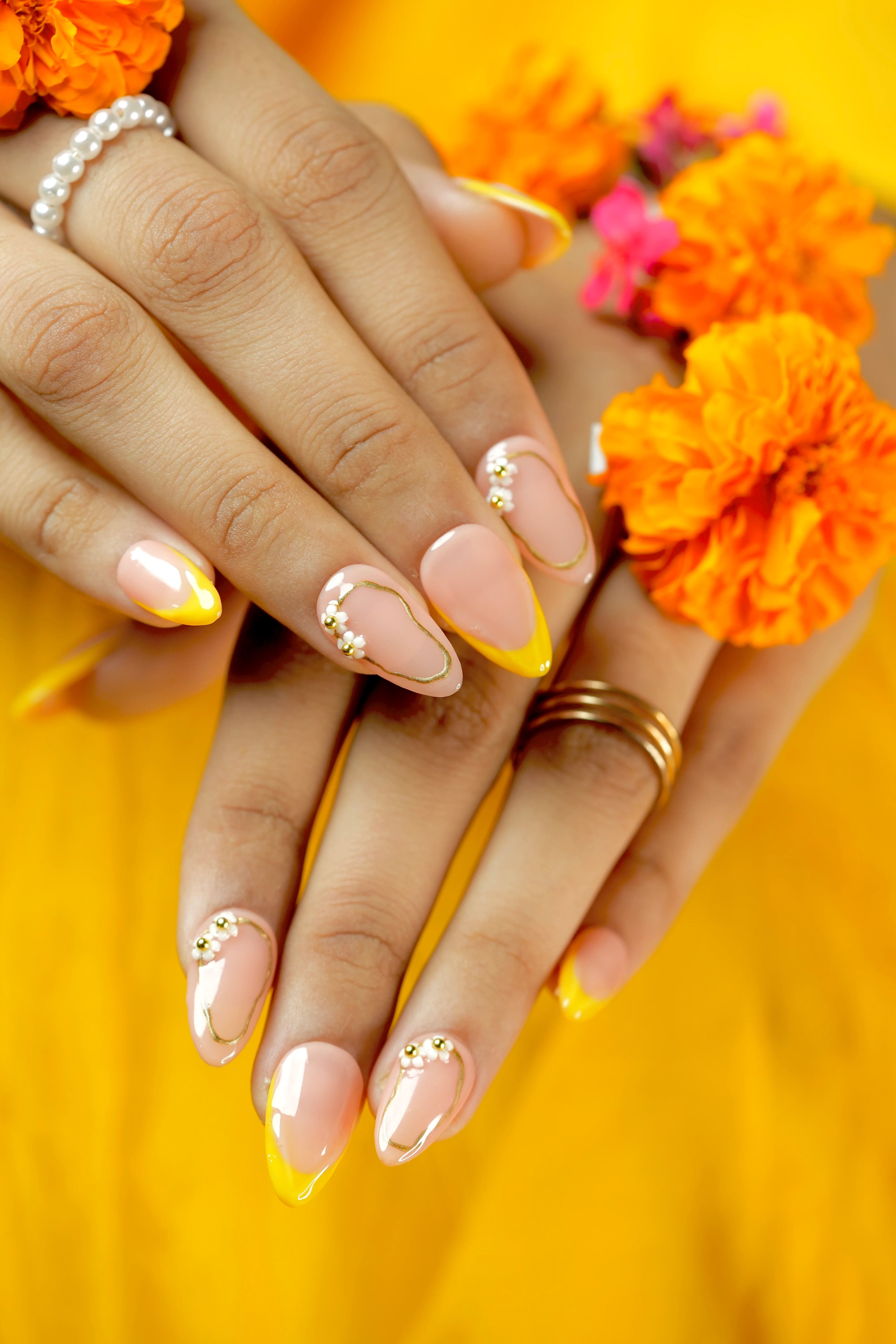 Yellow French tip almond nails with floral rhinestones